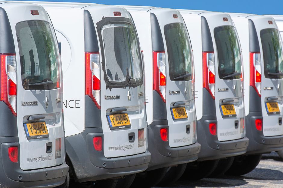 A row of white delivery vans parked outdoors, showcasing uniformity and logistics.